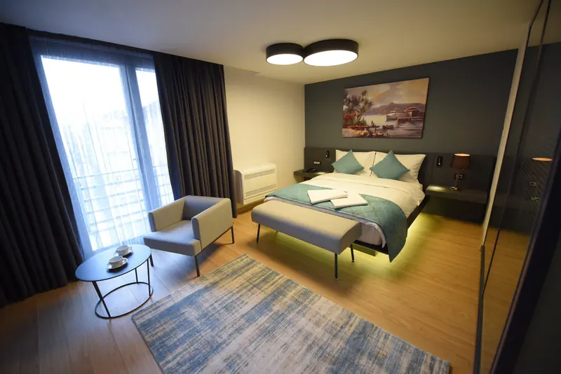 Deluxe Suit: geniş pencereli, ışıklı oda; çift kişilik yatak ve oturma köşesi