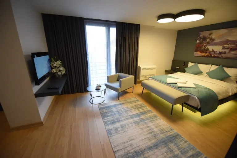 Deluxe Suit: çift kişilik yatak, koltuk, sehpa ve TV ünitesi